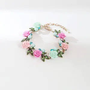 Detalle de una pulsera floral dulce con rosas de resina rosa y verde menta y perlas.