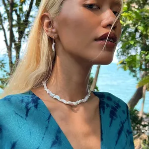 Détail d'un collier de perles d'eau douce irrégulières sur un mannequin face à la mer