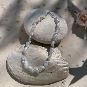 Vue détaillée d'un collier de perles d'eau douce en forme de croissant sur sable