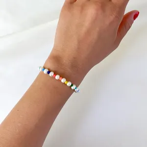 Gros plan d'un bracelet de perles d'eau douce et perles arc-en-ciel porté au poignet