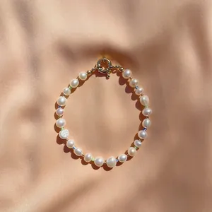 Gros plan d'un bracelet en perles baroques fait main avec perles arc-en-ciel sur soie pêche.