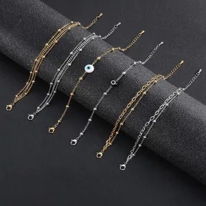 Vista detallada de pulseras de acero inoxidable en capas con ojo y cuentas en expositor
