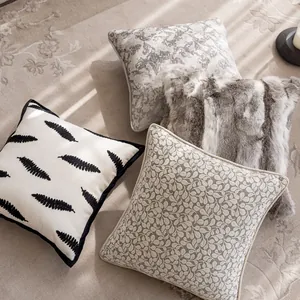 Overhead view of diverse textured cushion covers including faux fur and leaf embroidery.