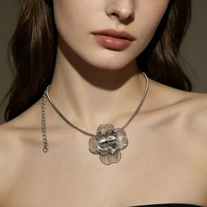 Gros plan d'un collier plastron fleur argentée avec des découpes en métal complexes