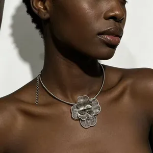 Vue détaillée d'un collier argenté avec une grande fleur ajourée portée par un modèle