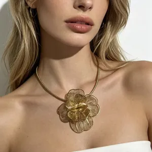 Gros plan d'un collier fleur dorée évidée exagéré avec des détails de pétales en fil.