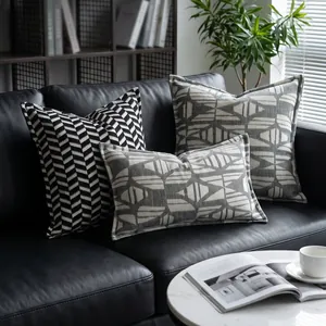 Detailansicht nordischer Retro-Kissenbezüge mit geometrischem Muster auf schwarzem Sofa