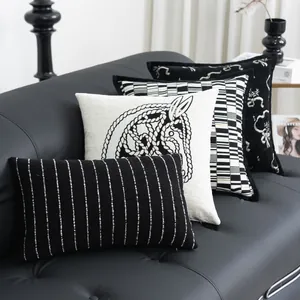 Stilvolle Anordnung von schwarz-weißen Dekokissenbezügen auf einem modernen Ledersofa.