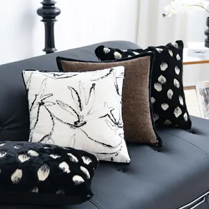 Detailansicht von Vintage-Kissenbezügen mit schwarz-weißem Muster auf Ledersofa.
