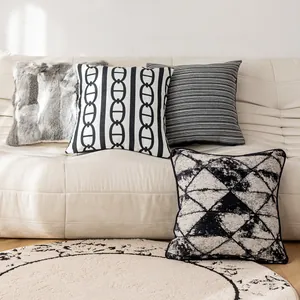 Kollektion von schwarz-weißen geometrischen Kissenbezügen auf einem beigen Ledersofa