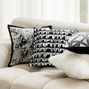 Detailaufnahme von schwarz-weißen geometrischen Kissenbezügen auf einem beigen Sofa