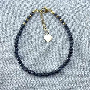 Close-up of bohemian blue natural stone beaded bracelet with gold heart charm.