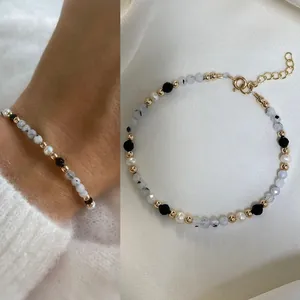 Detailed view of bohemian beaded bracelet with natural stones and pearls on white fabric.