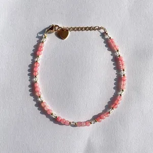 Close-up detail of Bohemian pink natural stone beaded bracelet featuring a gold heart charm