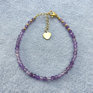 Bohemian purple amethyst beaded bracelet with gold heart charm on denim background