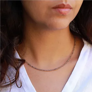 Gros plan d'un collier ras du cou minimaliste en pierres naturelles facettées grises porté