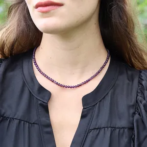 Gros plan d'un collier élégant en perles de pierre naturelle grise sur un mannequin.