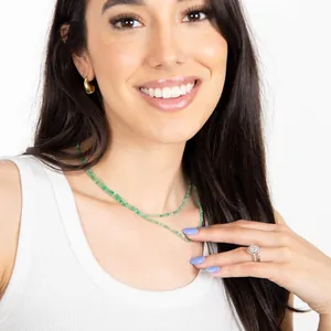 Détail d'une femme portant un collier de perles en pierre naturelle verte en couches.