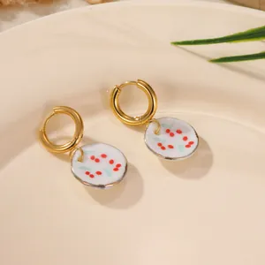 Close-up detail of 18K gold-plated hoop earrings with red floral ceramic charms