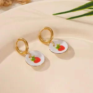 Close-up of 18K gold plated stainless steel hoop earrings with ceramic strawberry charms.