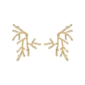 Detail of gold coral branch earrings with a luxury organic design for summer vacations