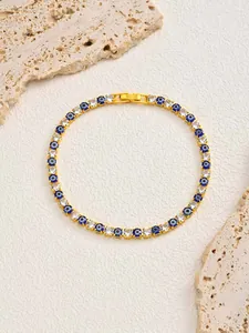 Detail view of gold-plated tennis bracelet featuring blue evil eyes and white zircons