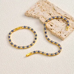 Detailed view of gold Evil Eye zircon bracelet and necklace set on stone prop