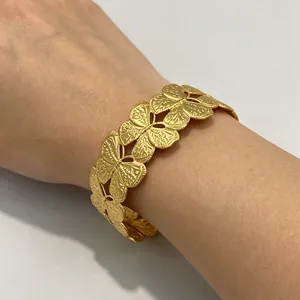 Detailansicht eines vintage goldfarbenen Edelstahl-Armreifs mit Blumen und Schmetterlingen
