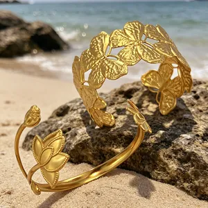 Vergoldete Edelstahl-Manschettenarmbänder mit Schmetterlings- und Lotusmotiv am Strand
