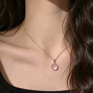 Gros plan d'un collier en argent avec pendentif rond en calcédoine rose sur le cou