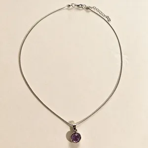 Vue détaillée d'un élégant pendentif en pierre violette sur une chaîne argentée fine