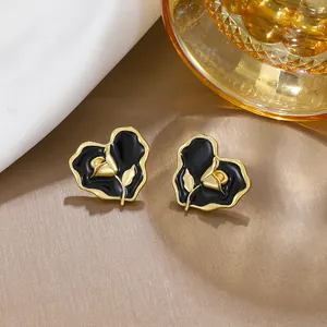 Close-up of vintage heart-shaped stud earrings with black enamel and golden rose motif