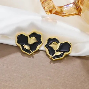 Macro detail of vintage heart-shaped stud earrings with elegant black rose enamel design
