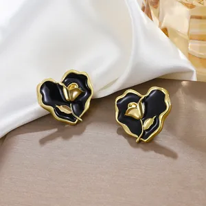 Detailed macro view of vintage heart-shaped earrings with black enamel and golden rose motif