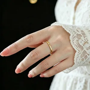 Detail eines minimalistischen Gold-Titanstahlrings mit kleinem Diamanten am Finger
