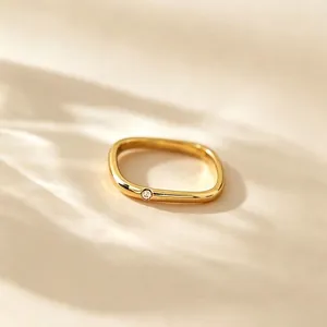 Nahaufnahme eines minimalistischen quadratischen Rings aus goldenem Titanstahl mit Stein
