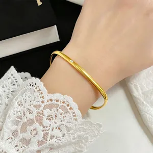 Detailansicht eines minimalistischen goldfarbenen Titanstahl-Armreifs mit einem Kristall