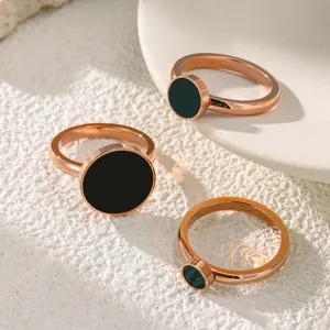 Primo piano di anelli minimalisti in titanio oro rosa con inserto circolare nero.