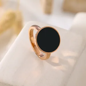 Primo piano di anello minimalista in acciaio al titanio oro rosa con intarsio in conchiglia nera.