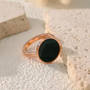 Dettaglio di anello minimalista in acciaio al titanio oro rosa con conchiglia nera.