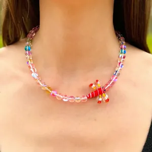 Vue détaillée d'un collier en perles de verre colorées avec un pendentif libellule.