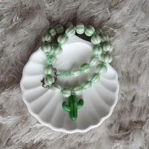 Détail du collier de perles fait main avec pendentif cactus vert sur plat.