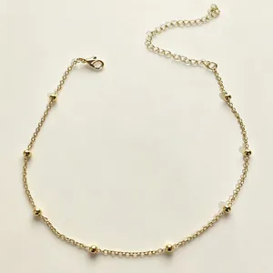 Detailansicht einer minimalistischen vergoldeten Perlen-Choker-Halskette auf Creme