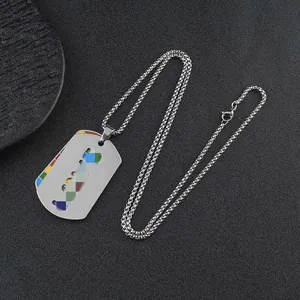 Detailed view of a rainbow dog tag necklace in stainless steel on a dark textured background.