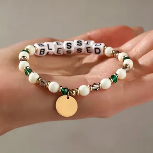 Nahaufnahme des 'BLESSED' Perlenarmbands mit grünen Kristalldetails und Goldanhänger