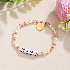 Nahaufnahme eines handgefertigten Perlenarmbands mit rosa Kristallen und MAMA-Buchstaben