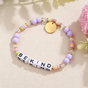 Makrodetail eines handgefertigten Perlenarmbands mit 'BE KIND'-Buchstabenperlen und Akzenten