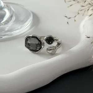 Vue détaillée d'une bague réglable argentée ornée de pierres facettées gris foncé.