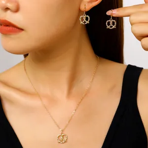 Primo piano di elegante set di collana e orecchini a forma di pretzel dorato con zircone