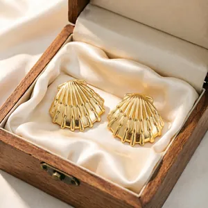Dettaglio di orecchini a conchiglia dorati in un portagioie di legno vintage